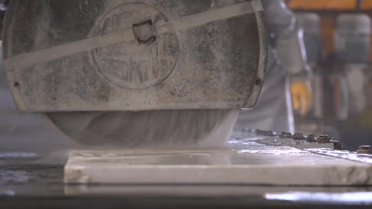 Worker Cutting Marble Slab with Industrial Saw in Stone Factory