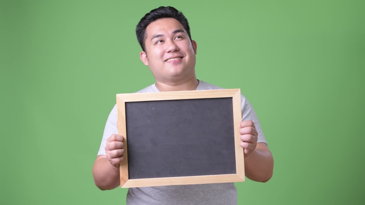 초록색 배경에 젊은 잘생긴 과체중 아시아인