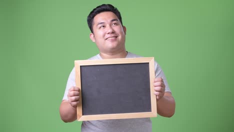 초록색 배경에 젊은 잘생긴 과체중 아시아인