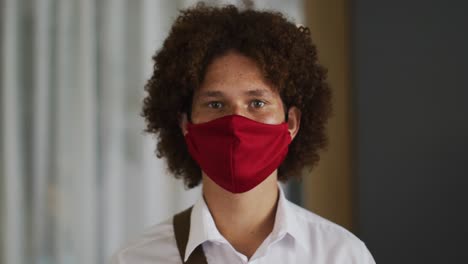 portrait of mixed race man with curly hair wearing red face mask