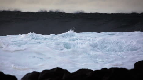 huge waves roll in and crash against a rocky shoreline 1