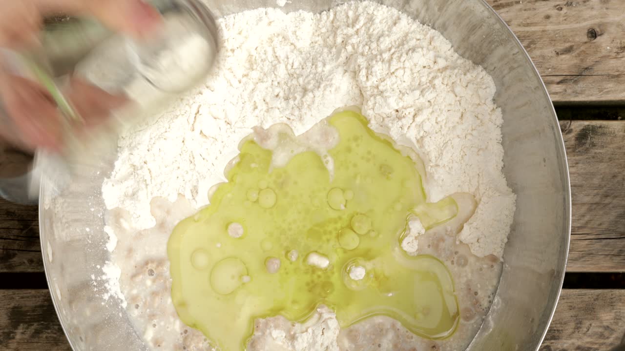 Mixing olive oil in a bowl of white flour and yeast