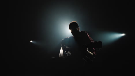 A-young-man-plays-the-guitar-sits-on-stage-4
