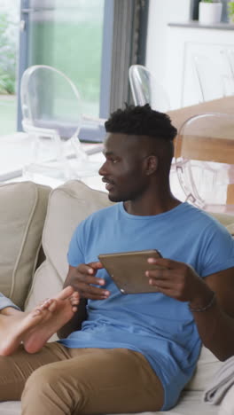 video de una feliz pareja afroamericana sentada en el sofá y usando un teléfono inteligente