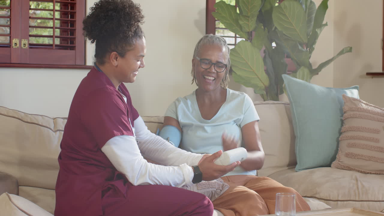 Checking blood pressure, caregiver ensuring senior woman's health and comfort at home