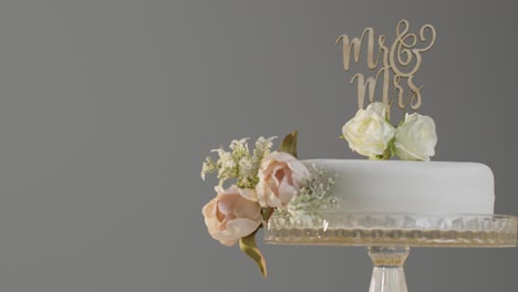 Primer-Plano-Del-Pastel-De-Bodas-En-El-Stand-Contra-El-Fondo-Gris-Del-Estudio-En-La-Recepción-De-La-Boda-1