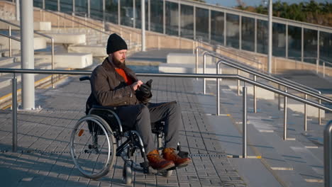 man in wheelchair using phone at outdoor ramp