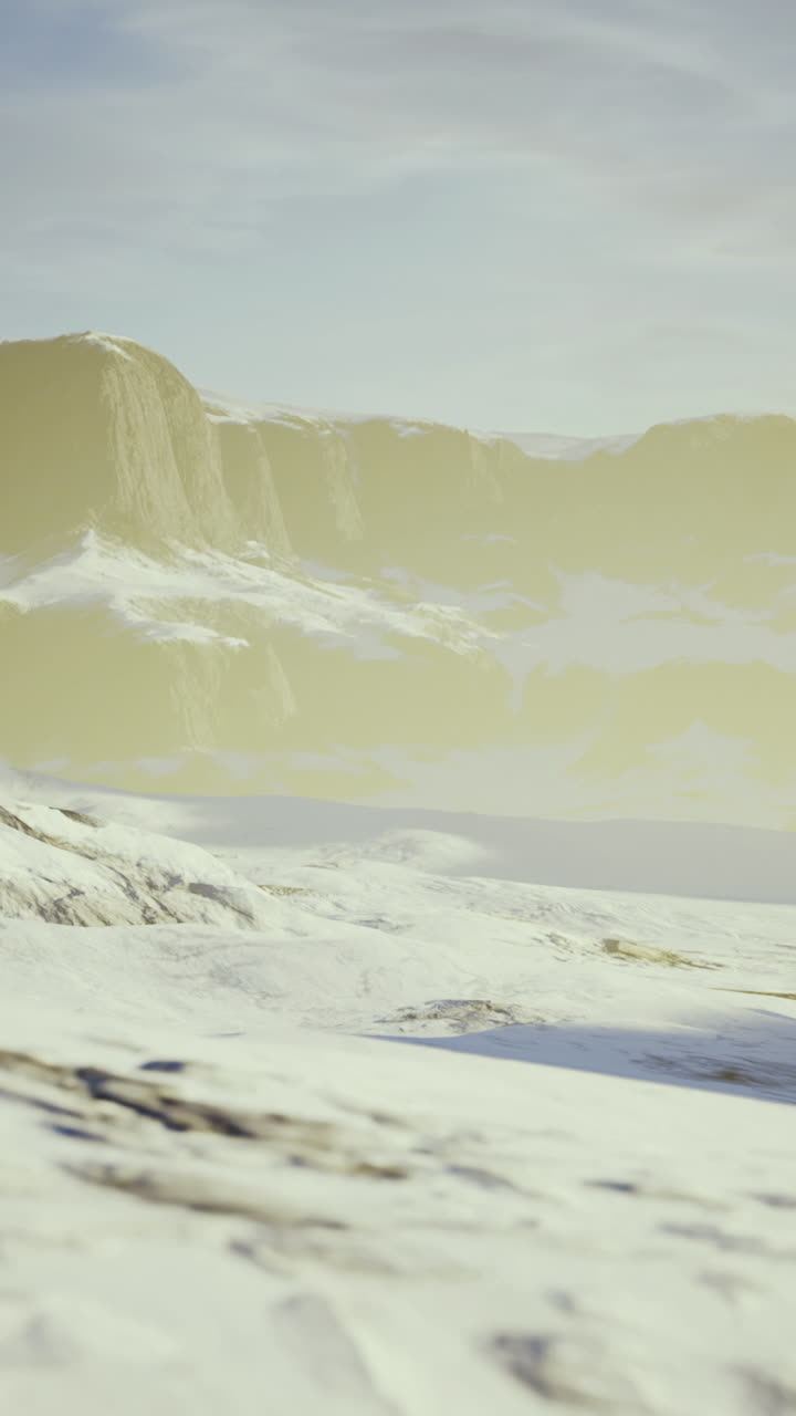 Snowy mountain landscape under a soft golden light at dawn