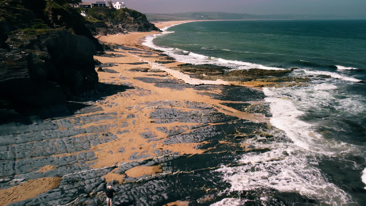 acantilados de devon y olas rompiendo en la playa de arena