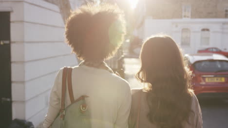 two beautiful friends walking using smart phone technology in sunny city