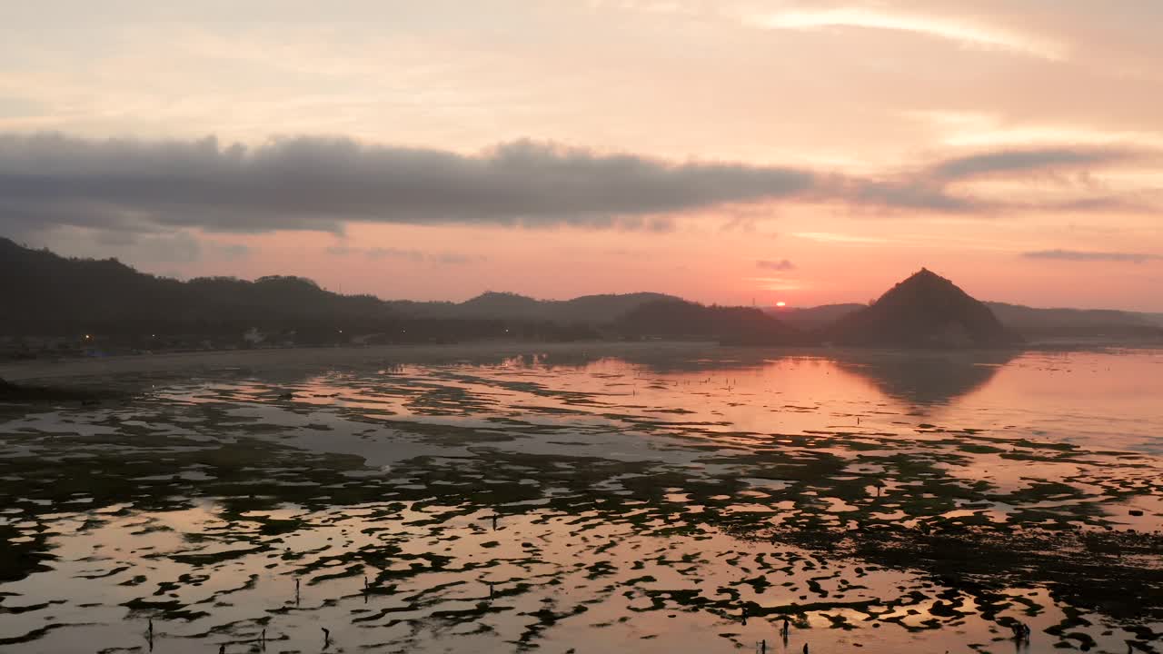 일출 동안 쿠타 롬복의 마른 암초, 현지 사람들이 음식과 조개껍질을 찾고 있습니다.