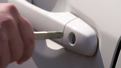 close up of a woman's hand manually unlocking a car with a key and then opening the door