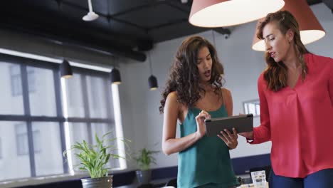 Diverse-female-colleagues-in-discussion-using-tablet-in-casual-office-meeting,-slow-motion