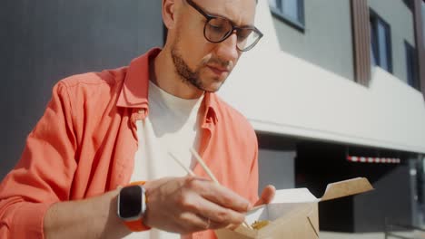 man eating asian noodles outdoors