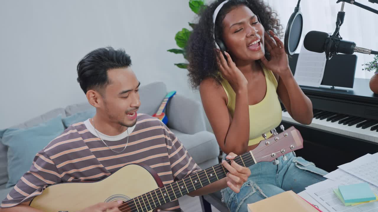 커플 이 홈 스튜디오 에서 노래 하고 음악 을 연주 하고 있다