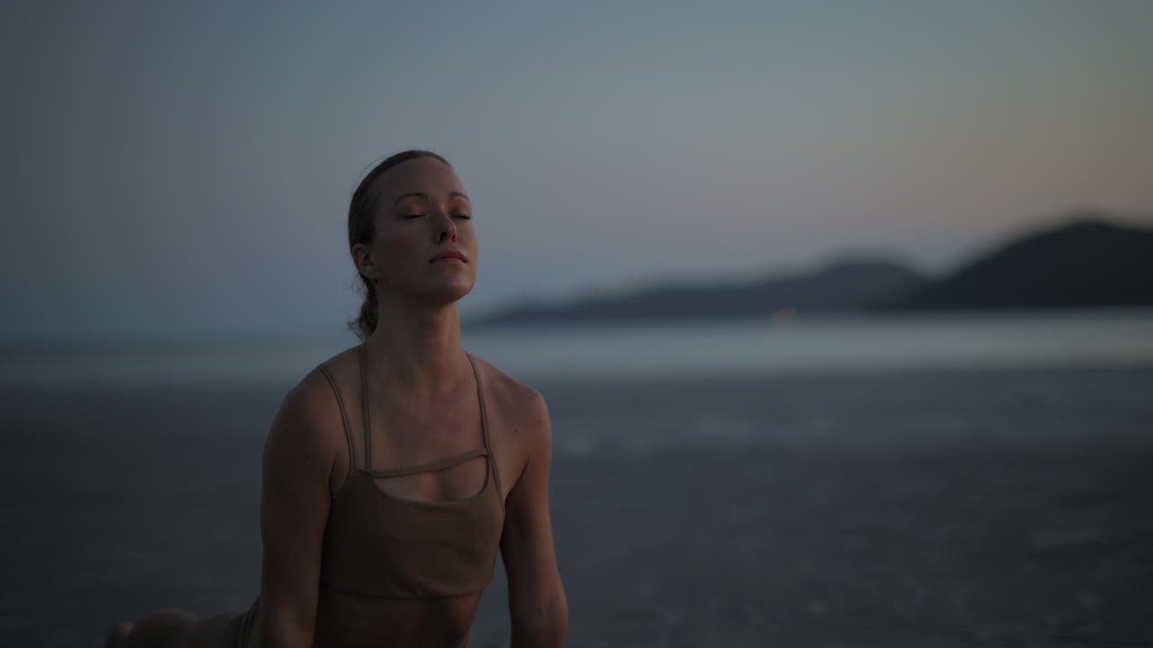 Woman in Upward-Facing Dog Yoga Pose on Beach at Dusk