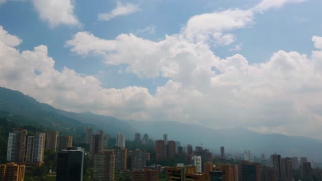 Antenne,-Drohne-Fliegt-über-Mehrfamilienhäuser,-Zeigt-Die-Skyline-Von-Medellin-In-Der-Ferne,-Blauer-Himmel