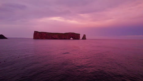 Vista-De-Drones-Alejándose-De-La-Roca-Percé-Durante-Una-Puesta-De-Sol-Nublada