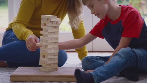 mother and son at home playing game stacking and balancing wooden blocks together