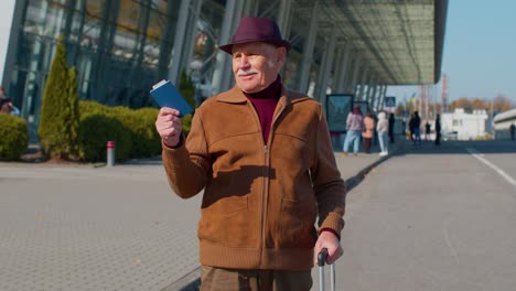 senior pensioner tourist grandfather stay near airport hall celebrate success win winner gesture