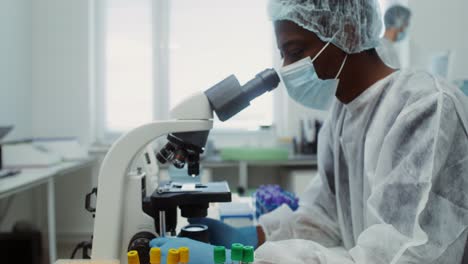 científico que trabaja con microscopio y tubos de ensayo en el laboratorio