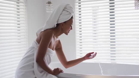 african american woman running her hand in the water in bathtub in the bathroom