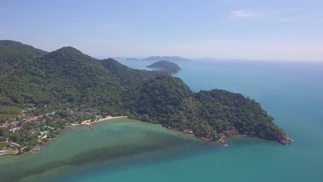 Toma-Aérea-De-Una-Isla-Tropical-Con-Montañas-Cubiertas-De-Selva,-Una-Playa-Y-Un-Océano