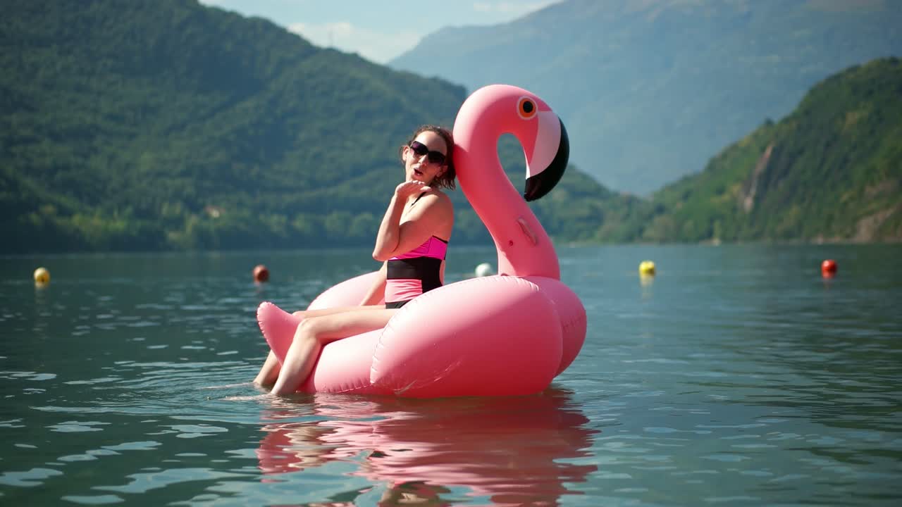 A women sitting on a pink flamingo inflatable on Lake Como, Italy