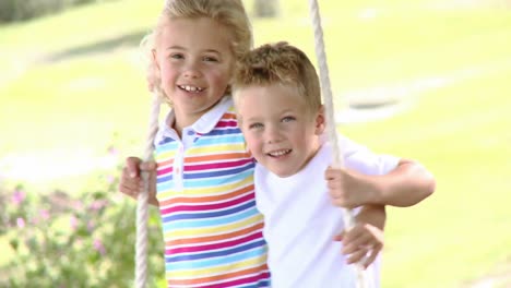 close up of siblings swinging in a park