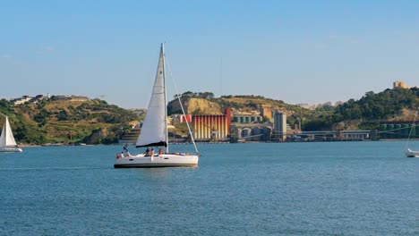 sailing boats cross root path at tagus river summer season sunny day in lisbon portugal near 25th of april bridge