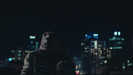 funny man wearing horse mask dancing on rooftop having fun performing silly dance moves celebrating weekend in urban city skyline