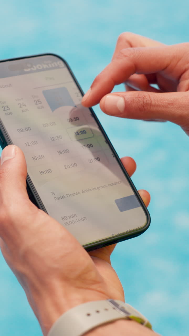 Close-up of Hands Using a Smartphone to Book an Activity Online