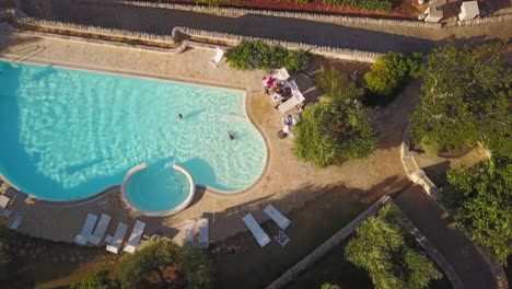 a drone shows a tourist swimming pool in italy in the countryside during the summer