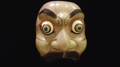 scary mask of topeng dance drama, wooden art of bali indonesia black background