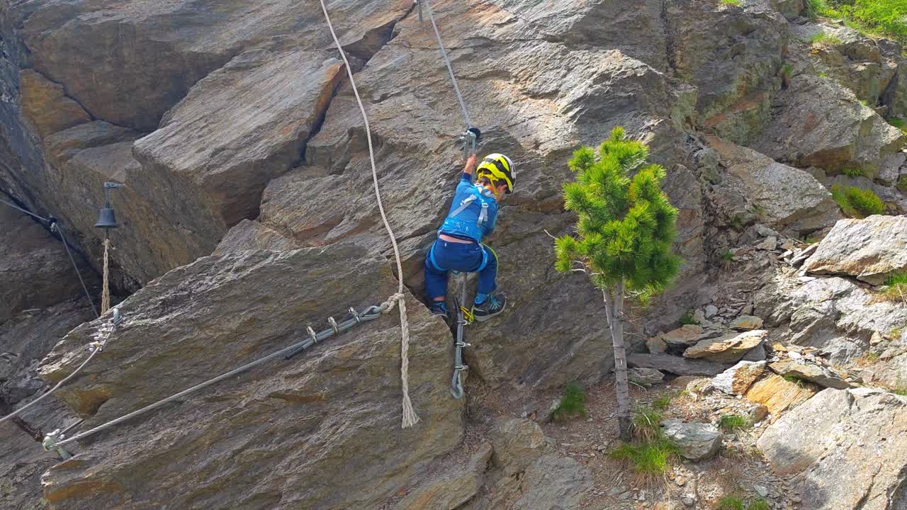 Slow motion view of young boy on via ferrata adventure in Dolomites, Italy, family outdoor adventure.