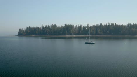 Velero-Blanco-Anclado-En-Las-Tranquilas-Aguas-De-Mayo-Cove-Cerca-De-Penrose-Point-State-Par-En-Lakebay,-Washington,-Estados-Unidos