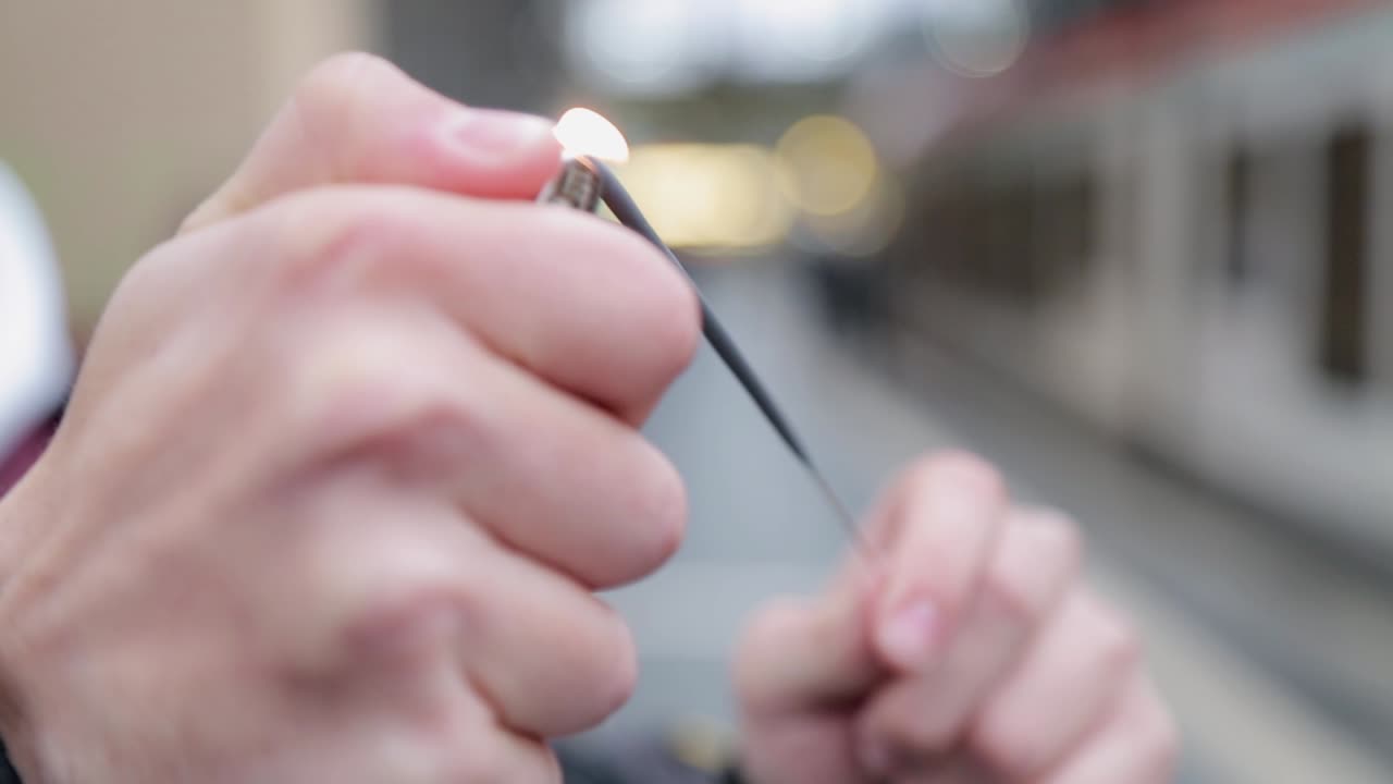 Hands lighting a spark in an outdoor setting with blurred background