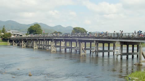 Panning-view-of-a-bridge-over-a-veautiful-river-in-Kyoto,-Japan-4K-slow-motion