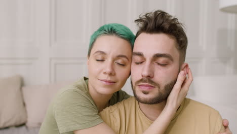 retrato de una pareja amorosa abrazándose sentada en la cama y mirando a la cámara