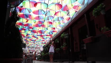 girl walking through umbrella street bucharest taking photos