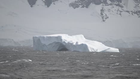 big ice berg with holes swims in ocean current