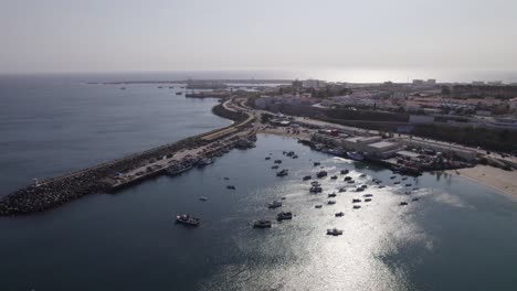 aerial forward over fishing boats in the coast of the city sines in portugal