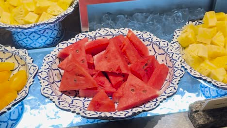 a colorful arrangement of watermelon, pineapple, and papaya slices on patterned plates, showcasing a fresh fruit selection.