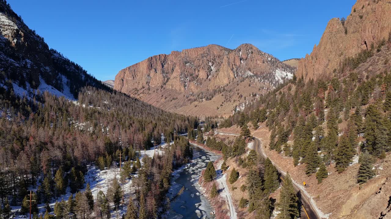 Filmato aereo professionale riprende un'auto che percorre una tortuosa autostrada di montagna attraverso una pineta verso le scogliere di Rio Grande Palisades in Colorado. Ideale per viaggi e marketing automobilistico.