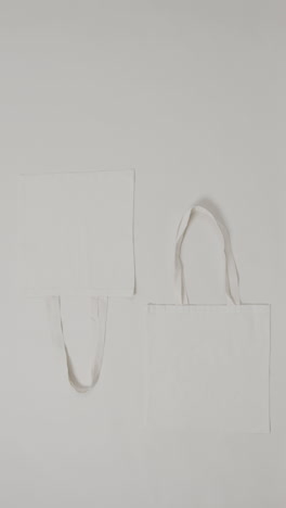 vertical video of white bags on grey background, copy space, slow motion