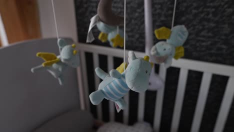 side dolly shot of an baby dragon soft toy hanging above the cradle