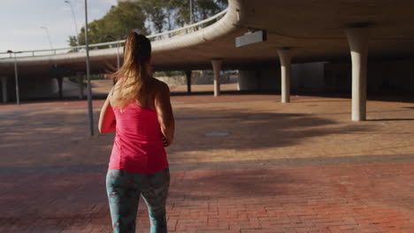 mujer caucásica corriendo debajo de un puente