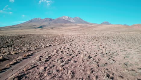 drone aterrizando en un remoto camino de grava en el desierto chileno con un volcán en el fondo