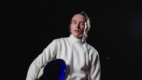 joven esgrimista en uniforme blanco sosteniendo su espada