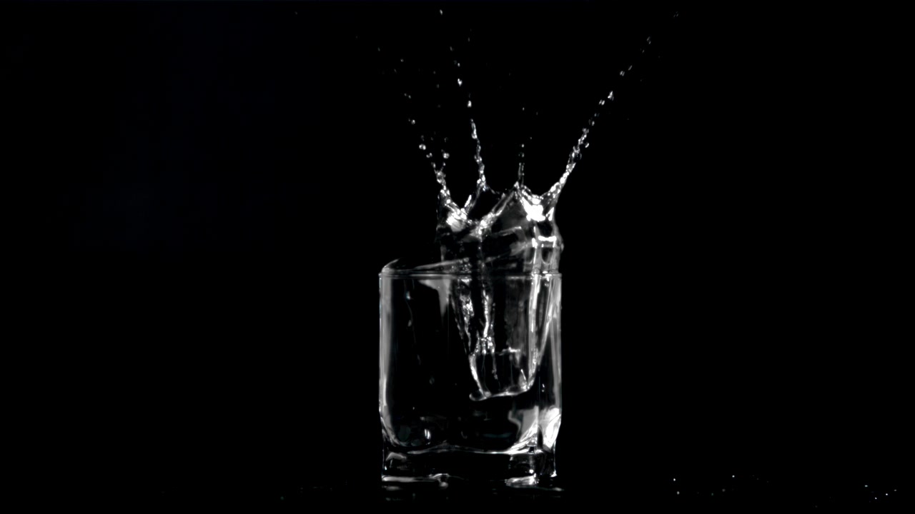 Cubetto di ghiaccio che si tuffa in un bicchiere d'acqua al rallentatore.